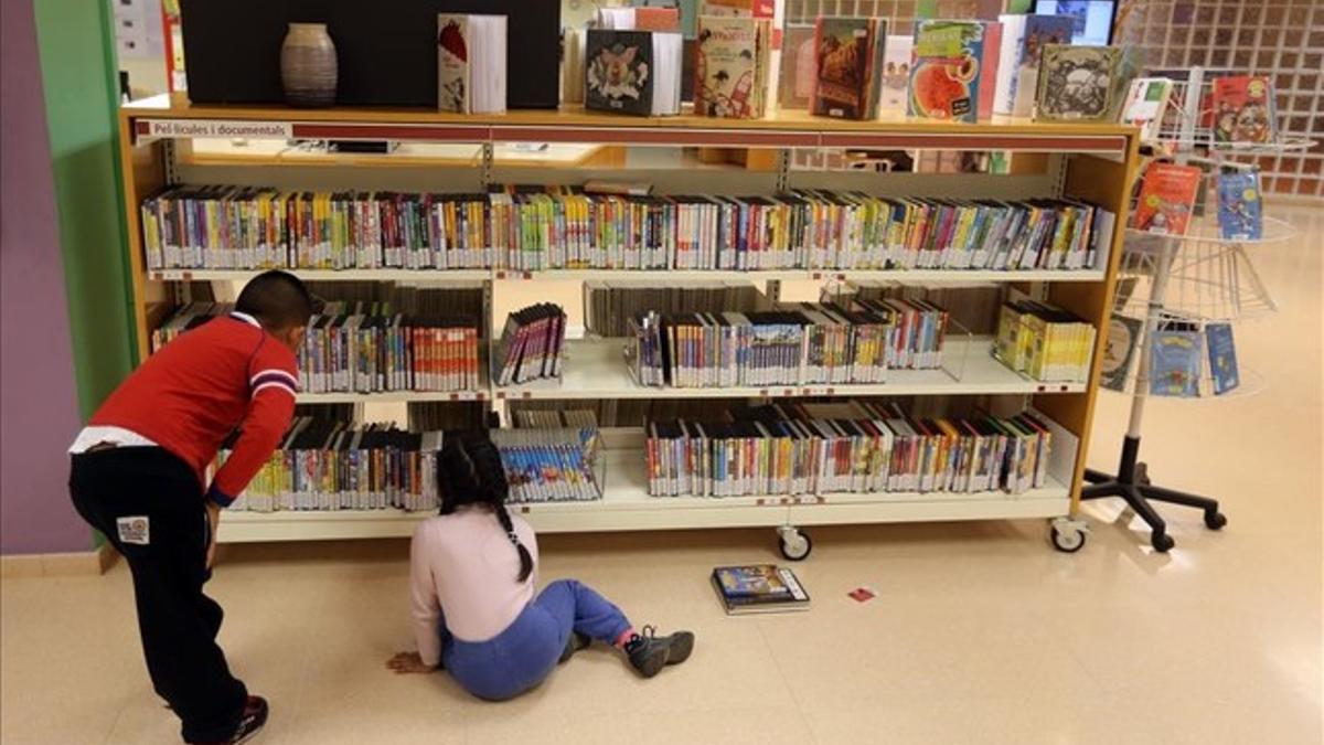 Dos niños consultan libros disponibles en la Biblioteca Central de Cornellà.