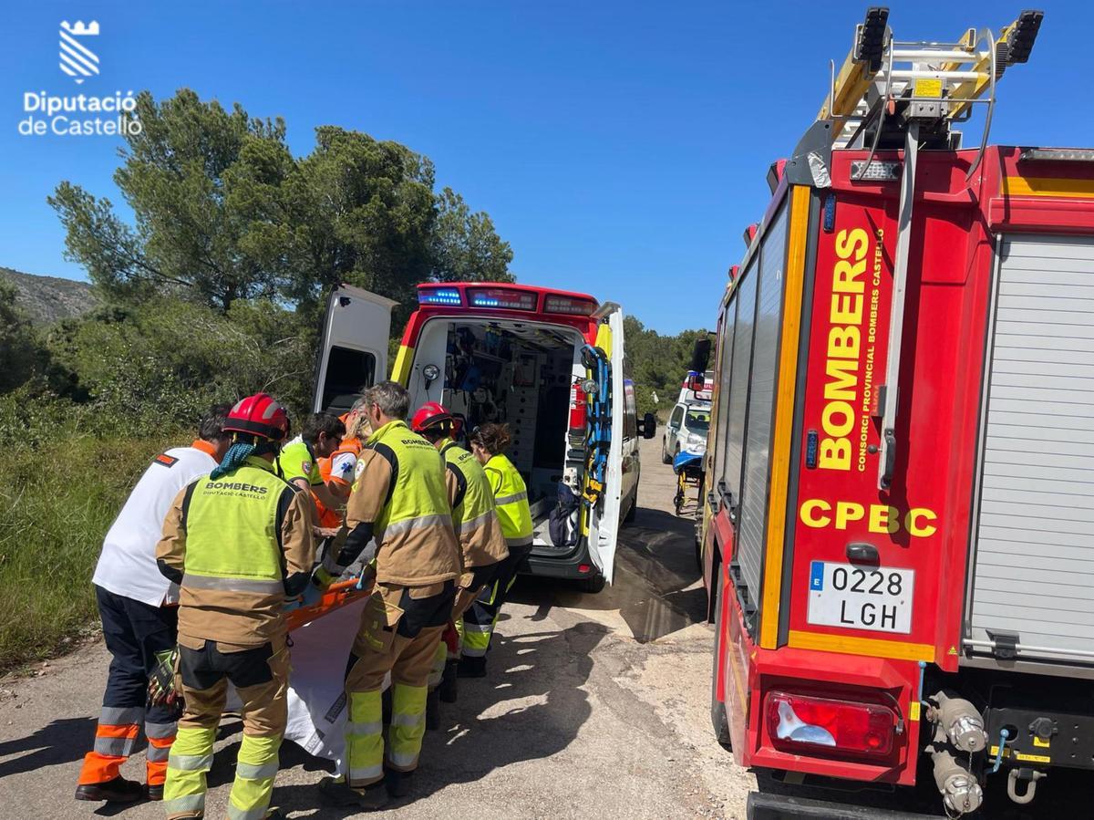 Bomberos y sanitarios trasladan al ciclista herido hasta la ambulancia tras ser rescatado de la zona forestal de Cabanes.