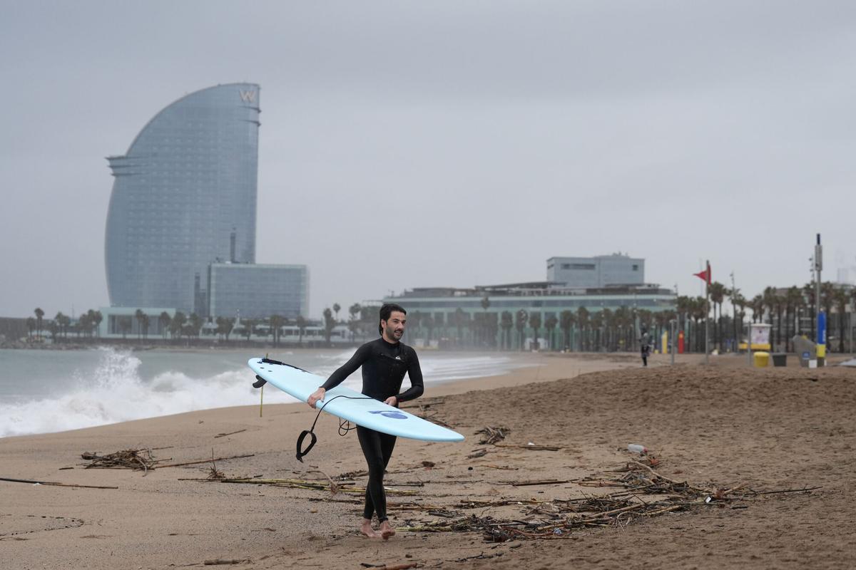 Un hombre practica surf durante el temporal, a 19 de enero de 2026, en Barcelona, Cataluña (España).