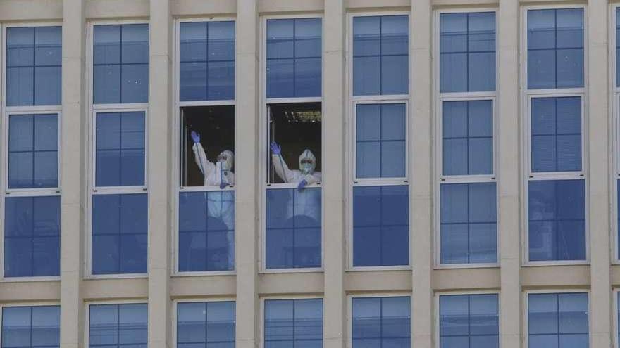 Dos sanitarios saludan ayer desde las ventanas del Hospital Provincial al recibir el último aplauso.