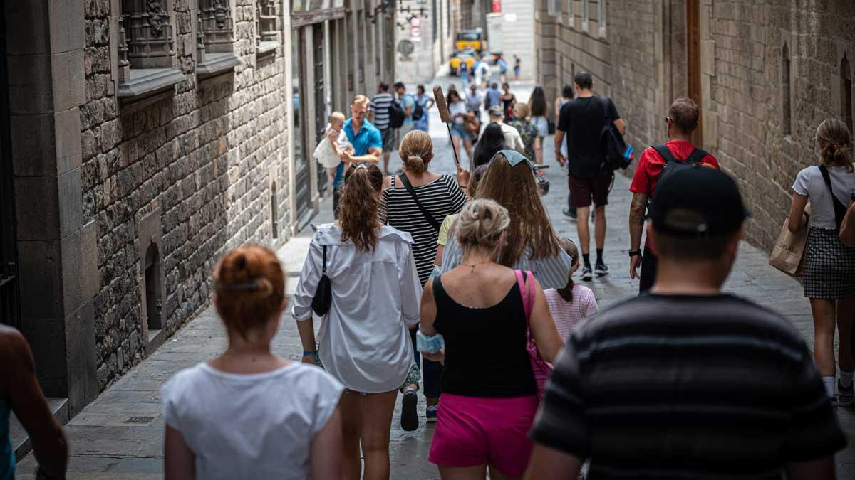 Un grupo de turistas siguen a su guía, por una calle de Ciutat Vella, en Barcelona