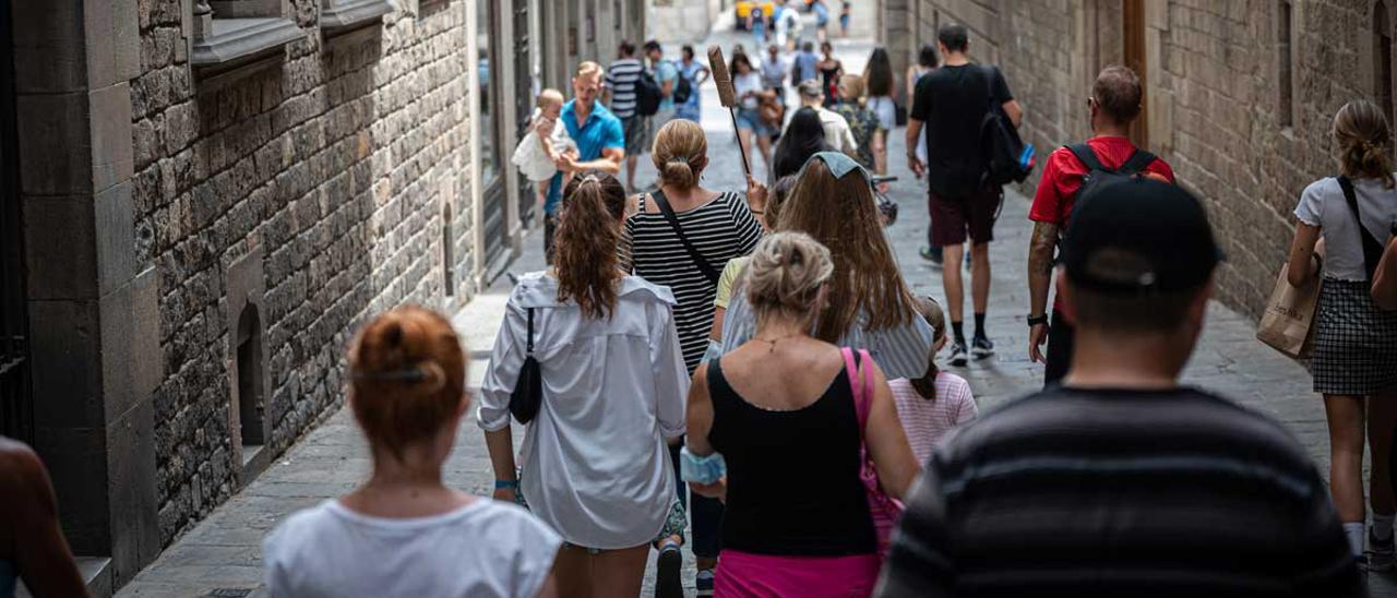 Un grupo de turistas siguen a su guía, por una calle de Ciutat Vella, en Barcelona.