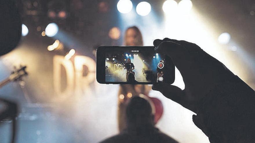 Un espectador recoge parte de un concierto con su móvil.