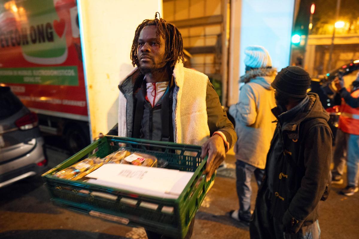 Voluntarios de distintas entidades privadas reparten comida para la cena de Nochebuena bajo la autopista C-31, donde aún duermen decenas de personas desalojadas del antiguo instituto B9