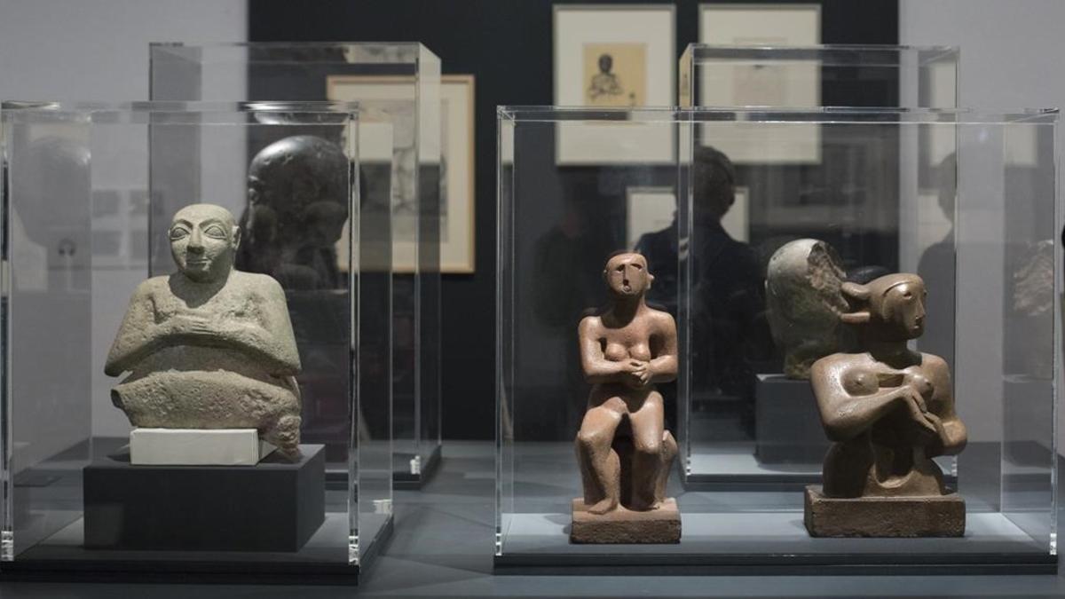 Figura de piedra sentada en actitud de oración del 2500 a.C. (izquierda) junto a dos esculturas de Henry Moore de 1929 expuestas en la Fundació Miró.