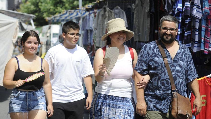 Visitantes en la feria de A Bandeira se abanican para combatir el calor. //Bernabé/Javier Lalín