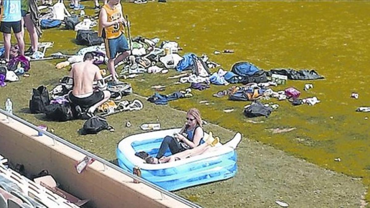 Jóvenes en una piscina, rodeados de desechos, en el campo del Reus.