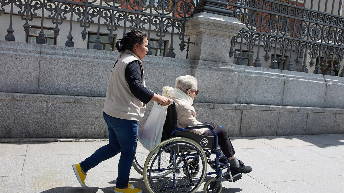 Una mujer mayor en silla de ruedas y su cuidadora