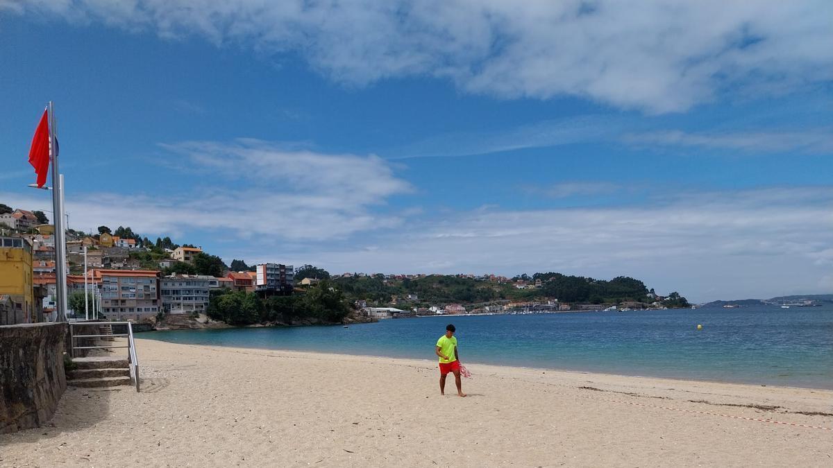 Un socorrista en la playa de Banda do Río, en Bueu, retirando el precinto y a punto de arriar la bandera roja en uno de los episodios de contaminación microbiológica del verano 2025.