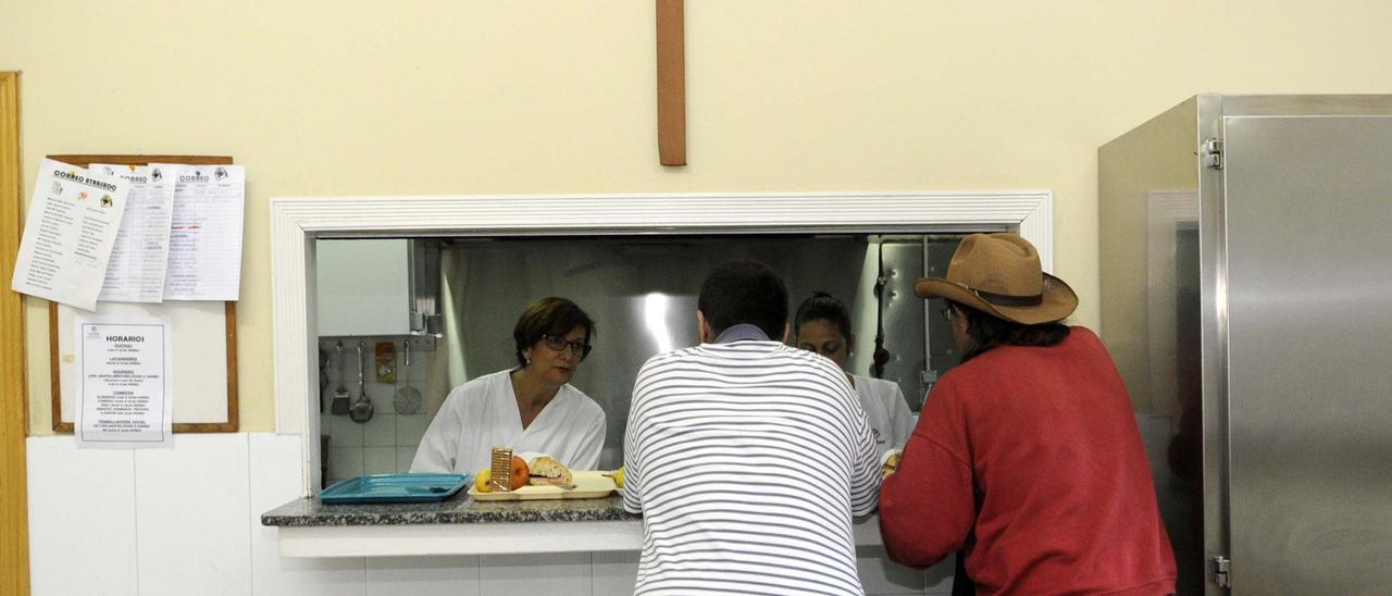 Dos usuarios reciben atención en un comedor social gestionado por Cáritas diocesana.