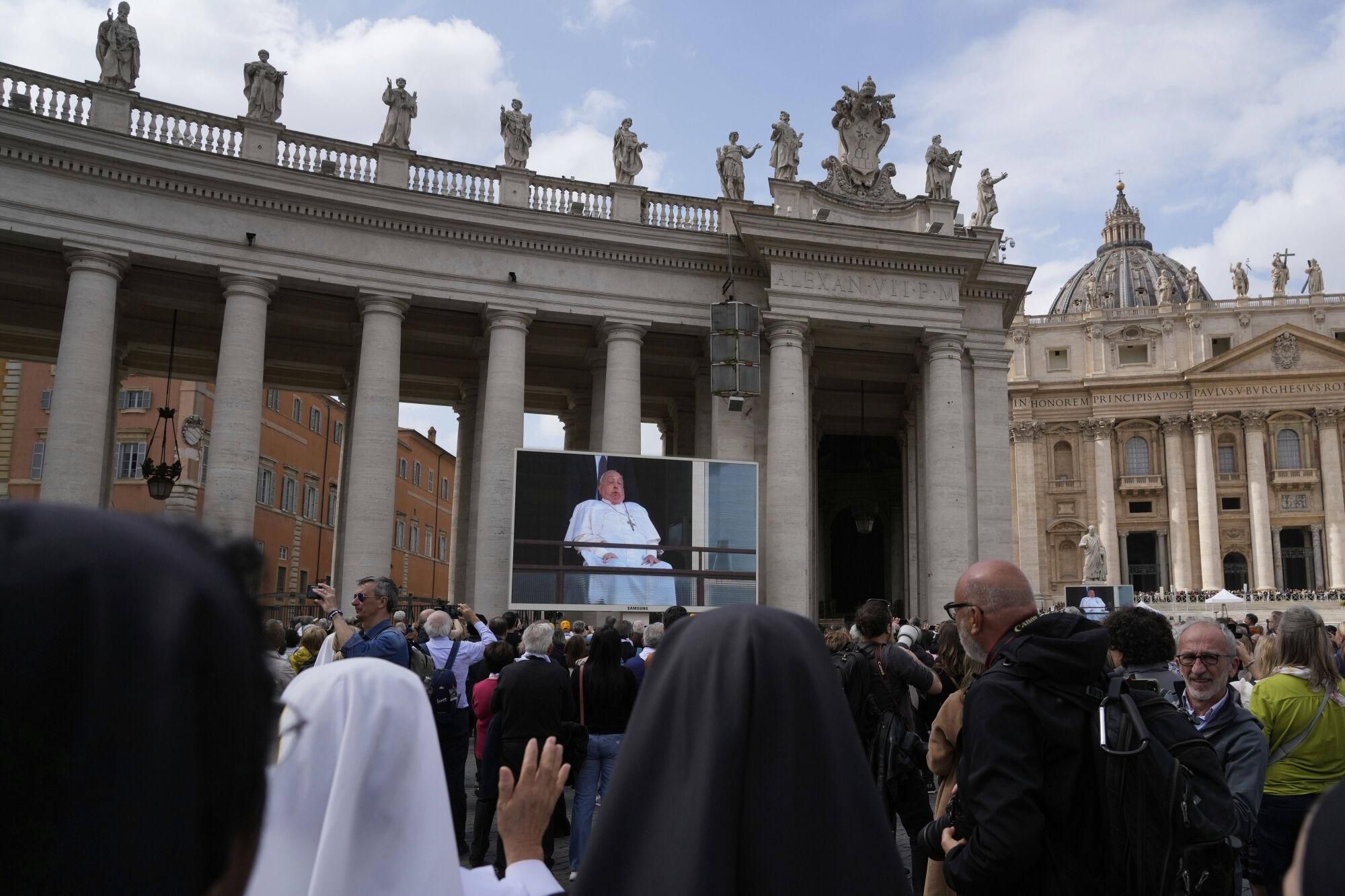 Nuns and faithful gather in St. Peter's Square at The Vatican to follow on giant screens a live broadcast from Rome's Agostino Gemelli Polyclinic, Sunday, March 23, 2025, where Pope Francis made his first public appearance since he was hospitalized on Feb. 14 with bilateral pneumonia. (AP Photo/Gregorio Borgia). EDITORIAL USE ONLY/ONLY ITALY AND SPAIN