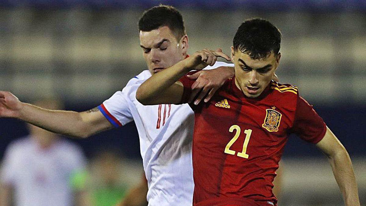 Pedri avanza con el balón presionado por un rival.