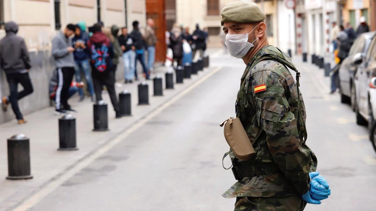 Un militar del Ejército de Tierra vigila a las puertas de un comedor social en Murcia.