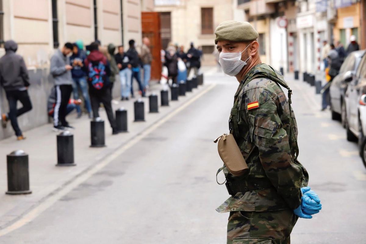 GRAF078. MURCIA, 21/03/2020.- Un militar del Ejército de Tierra mantiene orden ante un comedor social de la capital, durante la mañana del séptimo día de estado de alarma en Murcia. EFE/Juan Carlos Caval