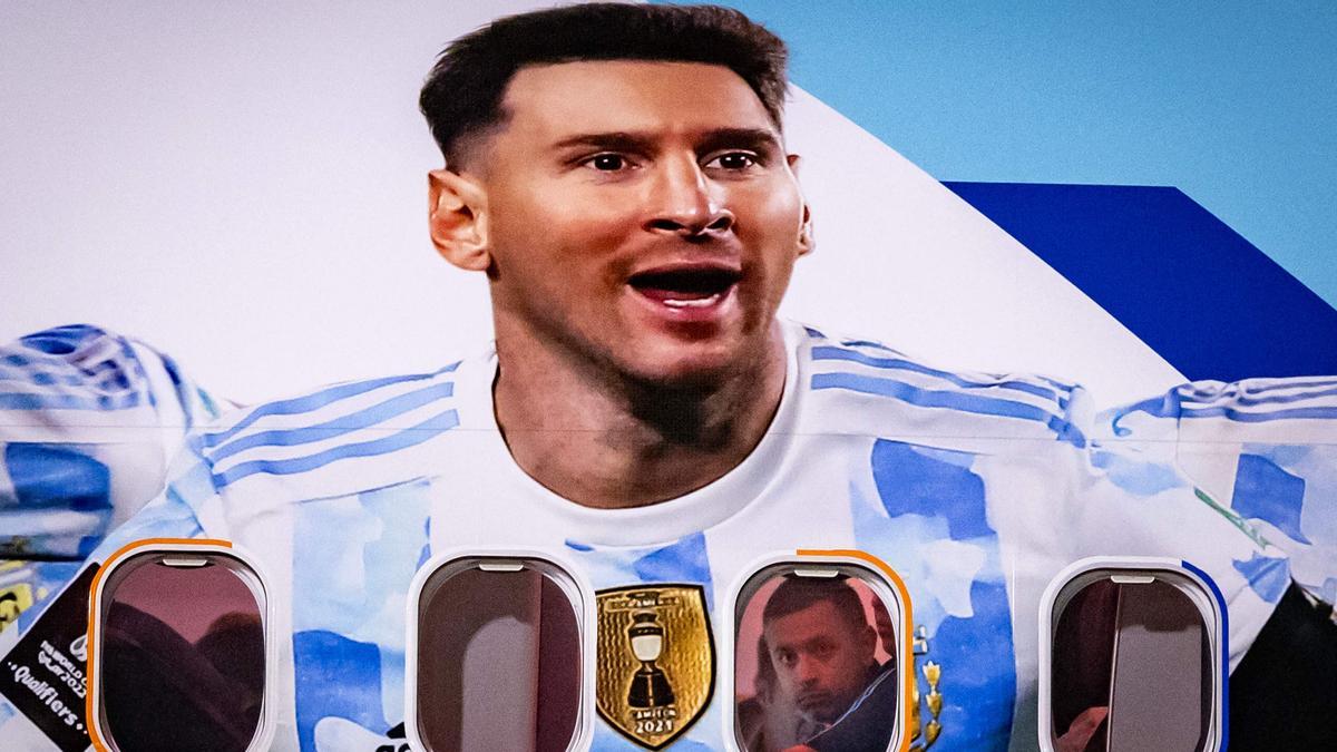 Los miembros del equipo argentino miran desde las ventanas de su avión adornado con una imagen del delantero argentino Lionel Messi en la llegada del equipo al Aeropuerto Internacional Hamad, en Doha