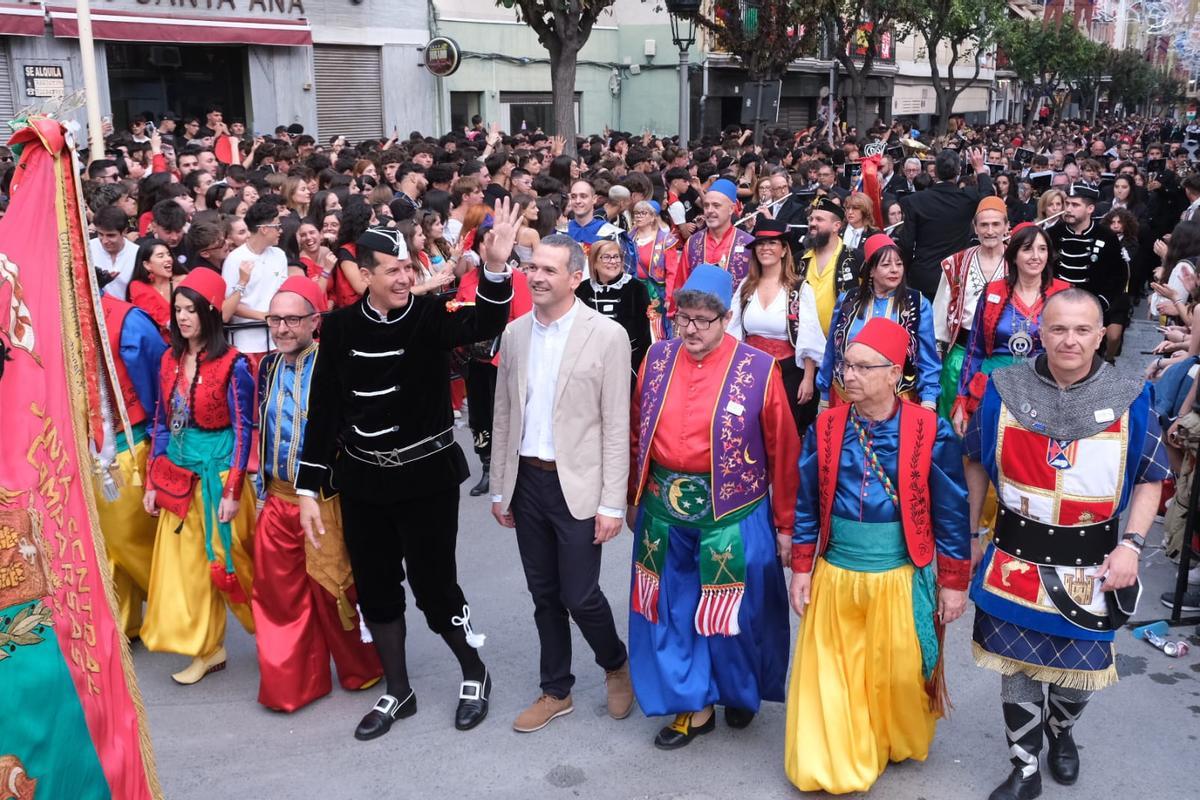 El alcalde saludando al público y a su lado y el director del pasodoble Idella y el presidente de la Junta Central de Comparsas.