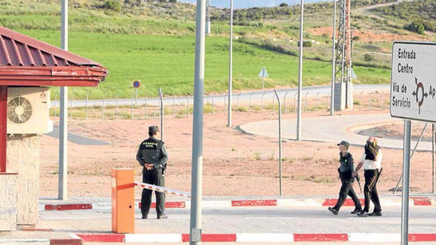 Un vigilante privado -tapándose la cara- ayer junto a dos guardia civiles en la cárcel de Villena.