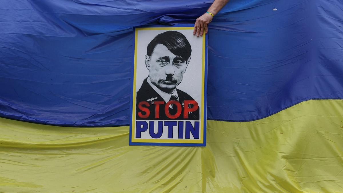 Un miembro de la Asociación Ucraniana de Sudáfrica sostiene un cartel que representa al presidente ruso Vladimir Putin como Adolf Hitler durante una protesta en apoyo de Ucrania frente a la embajada rusa en Pretoria, el 25 de febrero de 2022.