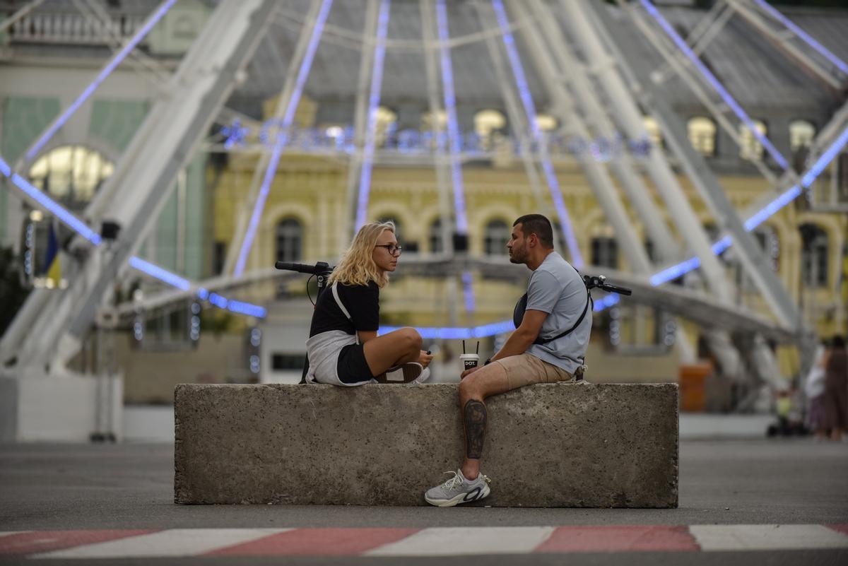 Una pareja junto a la noria de la ciudad