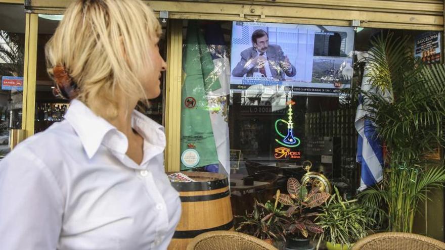 Una camarera mira los programas sobre el dictador en un bar del centro de Alicante.