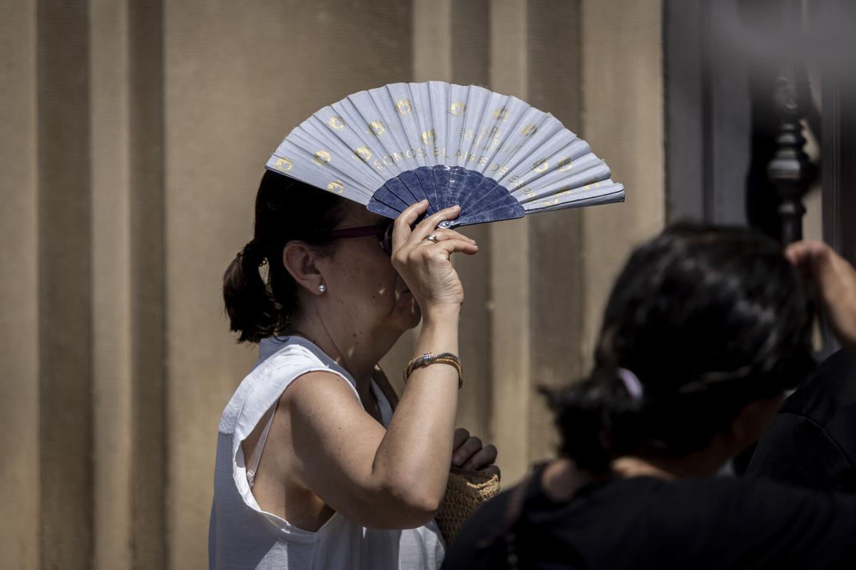 Una mujer en el centro de Zaragoza protegiéndose del sol con un abanico