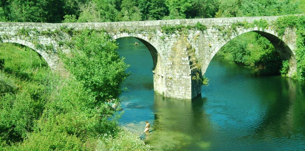 El puente medieval de Comboa, ayer, con una bañista. | A.P.