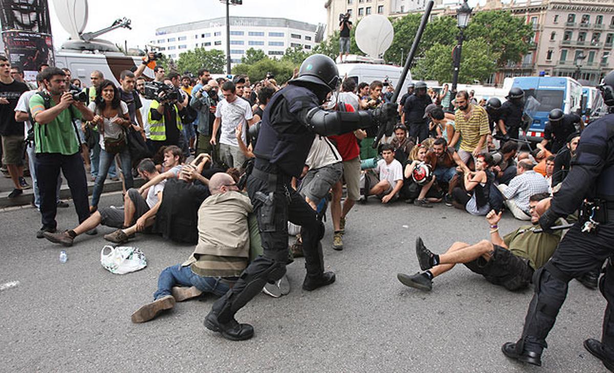 Els agents antiavalots peguen amb porres a alguns manifestants de la plaça de Catalunya.
