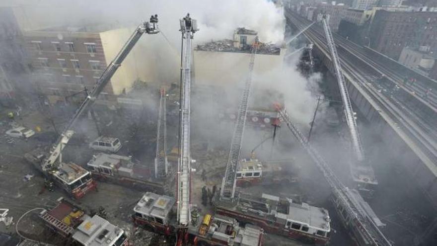 Los camiones de bomberos sofocan el fuego en el inmueble de Harlem donde se produjo el incendio. / j. lane