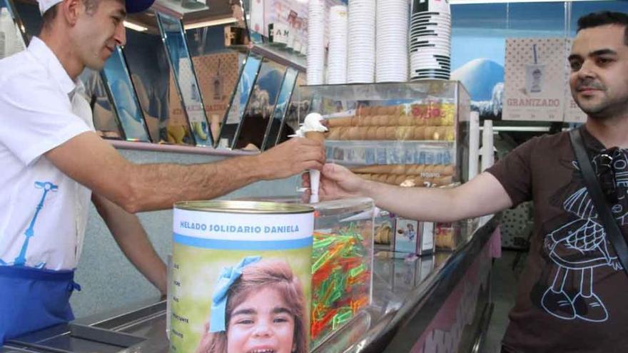 Un cliente compra su helado después de introducir el dinero en la hucha.