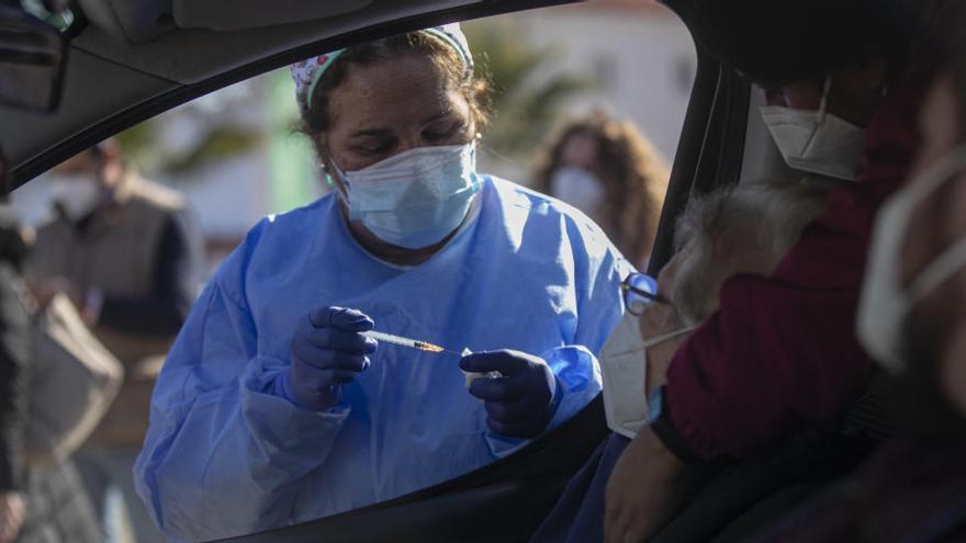 Una mujer mayor de 90 años recibe desde el coche la vacuna de Pfizer en Sevilla
