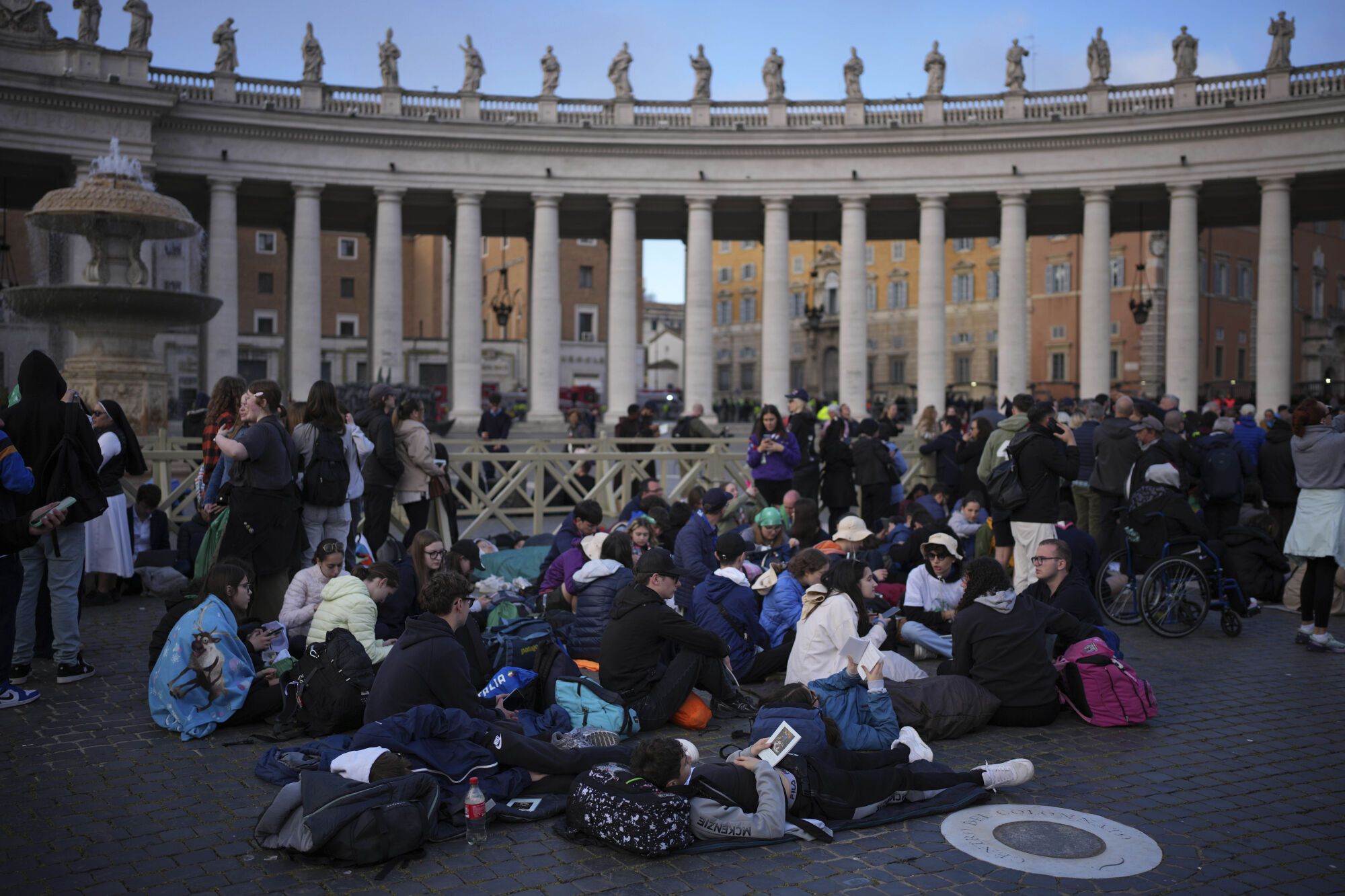 Faithful sit in St. Peter's Square waiting for the funeral of Pope Francis to begin, at the Vatican, Saturday, April 26, 2025. (AP Photo/Emilio Morenatti)