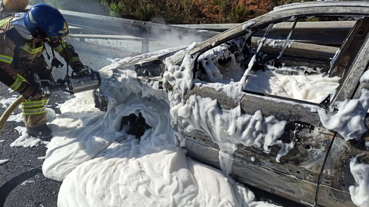 Un bombero trabaja en las labores de extinción del fuego que ha calcinado el turismo