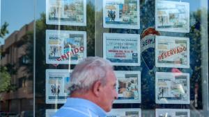 Imagen de archivo de un hombre caminando frente escaparate de una inmobiliaria