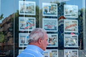 Imagen de archivo de un hombre caminando frente escaparate de una inmobiliaria