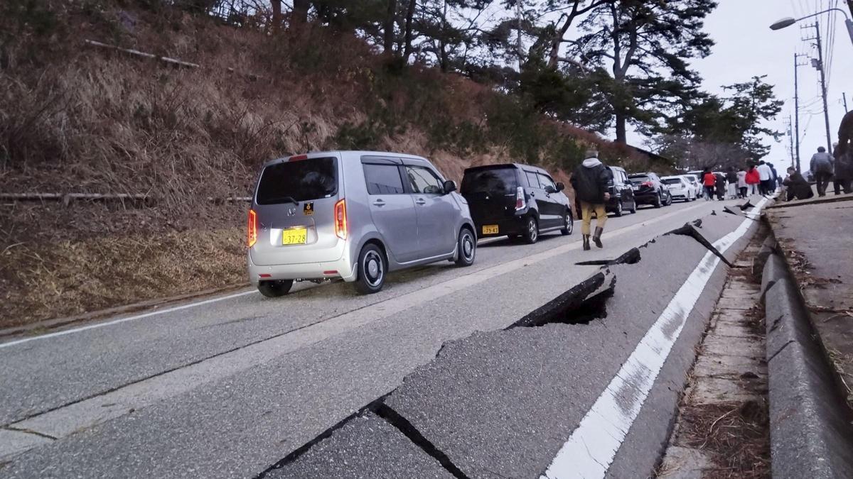 La gente camina junto a la carretera partida por el efecto de un terremoto en Wajima, prefectura de Ishikawa en Japón