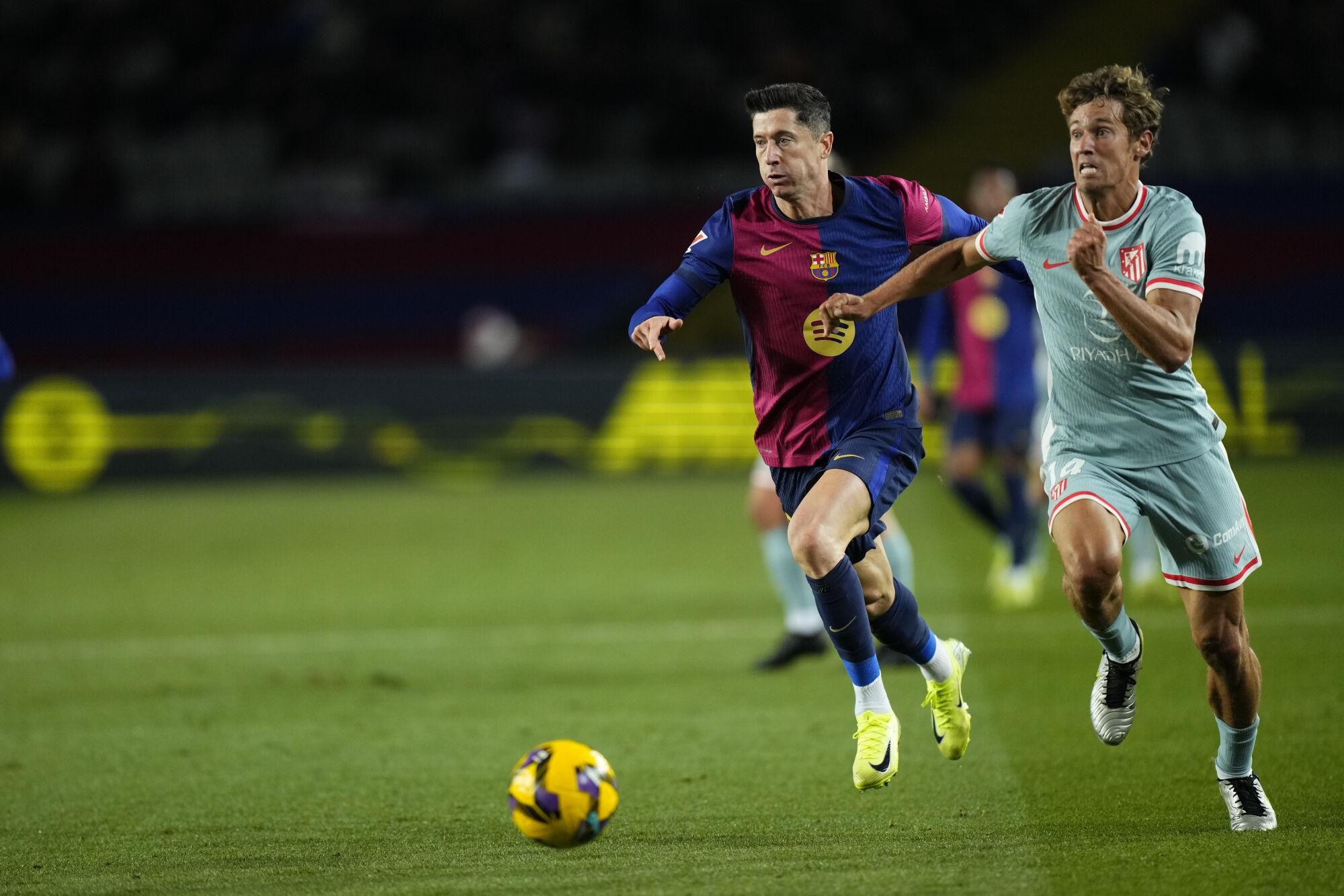 BARCELONA, 21/12/2024.- El delantero polaco del FC Barcelona Robert Lewandowski (i) persigue a Marcos Llorente, del Atlético de Madrid, durante el partido de la jornada 18 de LaLiga entre el FC Barcelona y el Atlético de Madrid, este sábado en el estadio olímpico Lluis Companys. EFE/Siu Wu
