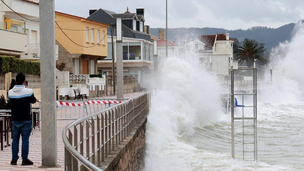 El temporal provoca un tren de olas en Panxón que arrasa su arenal y bate contra el paseo.