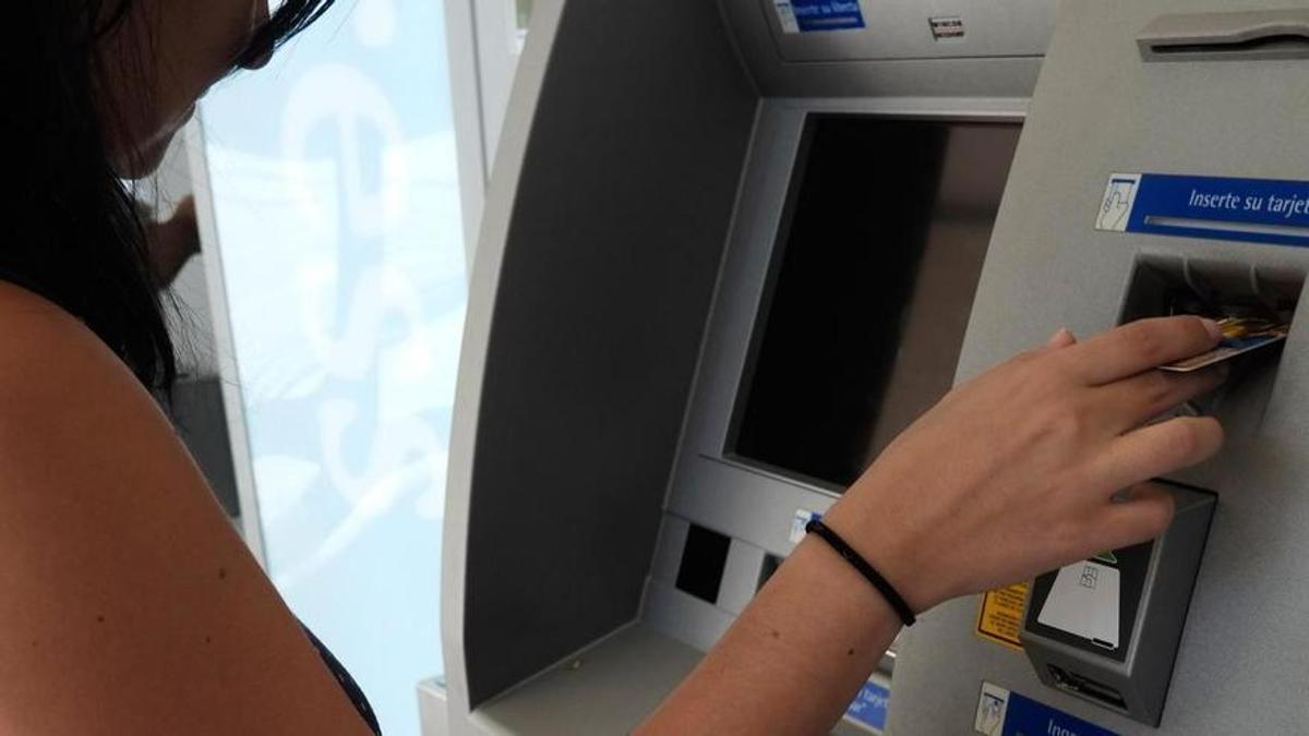Mujer saca dinero de un cajero automático, imagen de archivo.