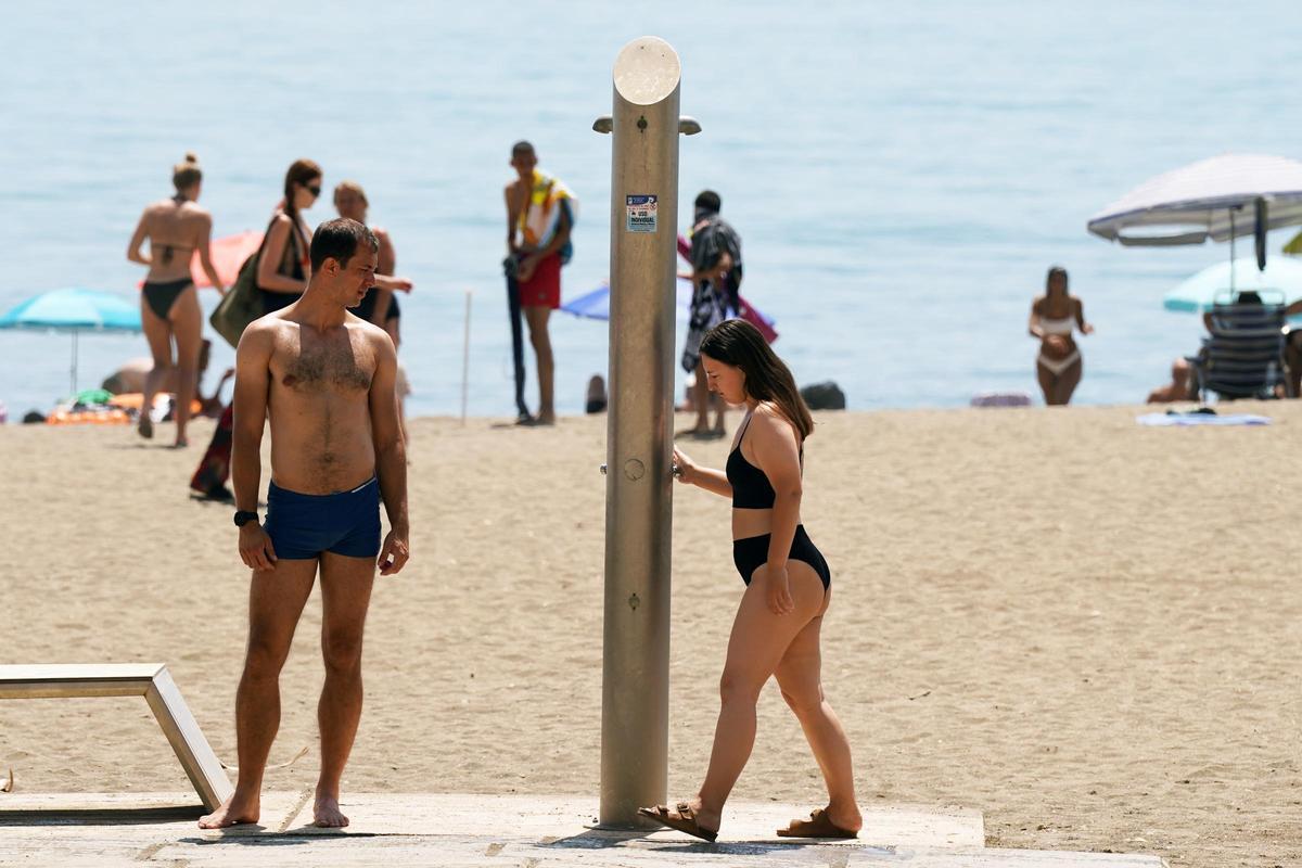 Usuarios de las playas de Málaga usan las duchas y lavapiés días antes de que corten en el agua. Agosto de 2023.