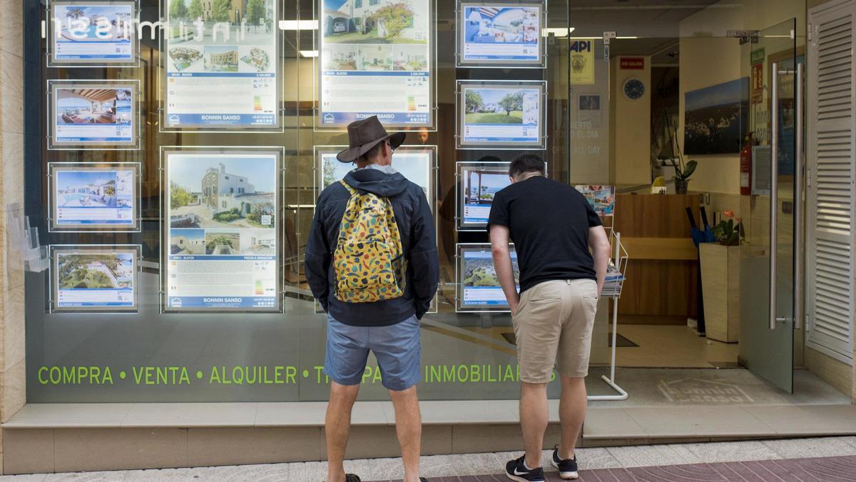 Dues persones davant l’aparador d’una immobiliària.