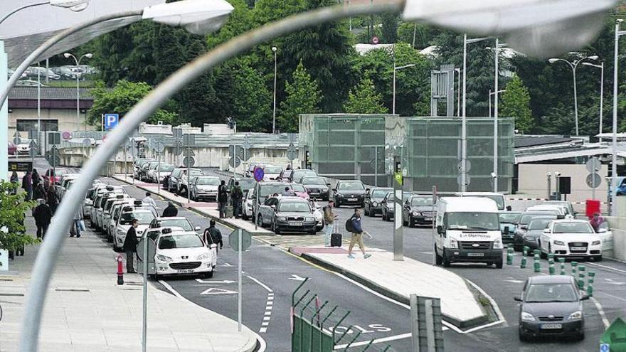 Vial de acceso a Peinador con multitud de coches mal aparcados junto al parking (derecha).