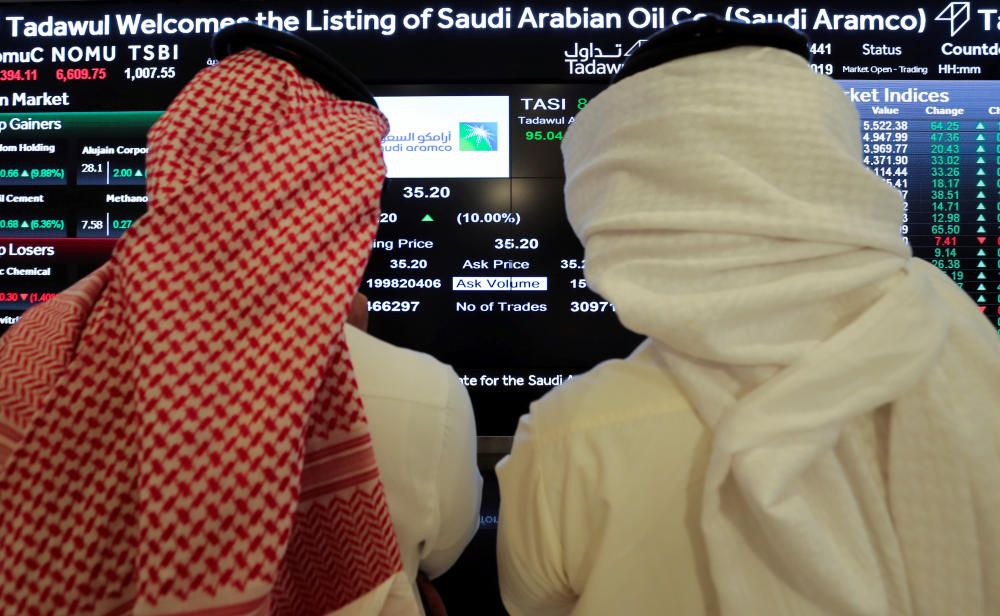 Investors monitor a screen displaying stock ...