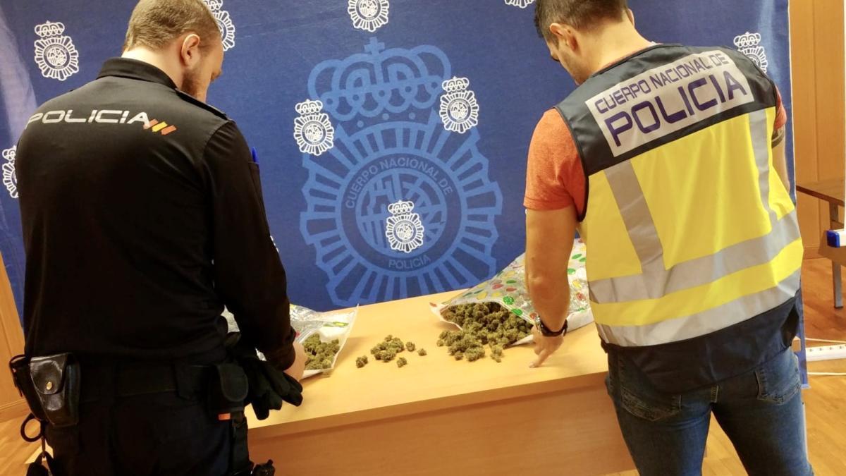 Dos policías examinan la droga intervenida al detenido.