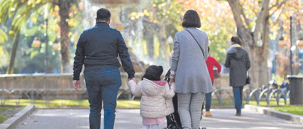 Una pareja pasea con una niña en el parque.