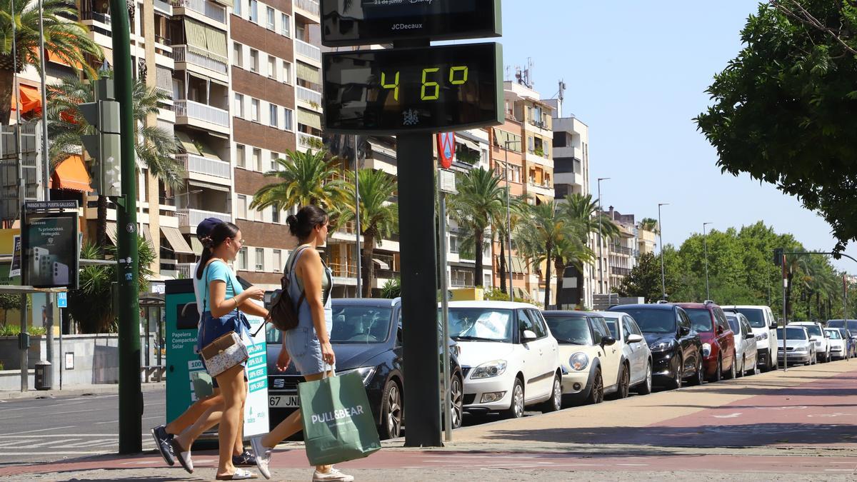 Varias personas pasean junto a un termómetro urbano en Córdoba.