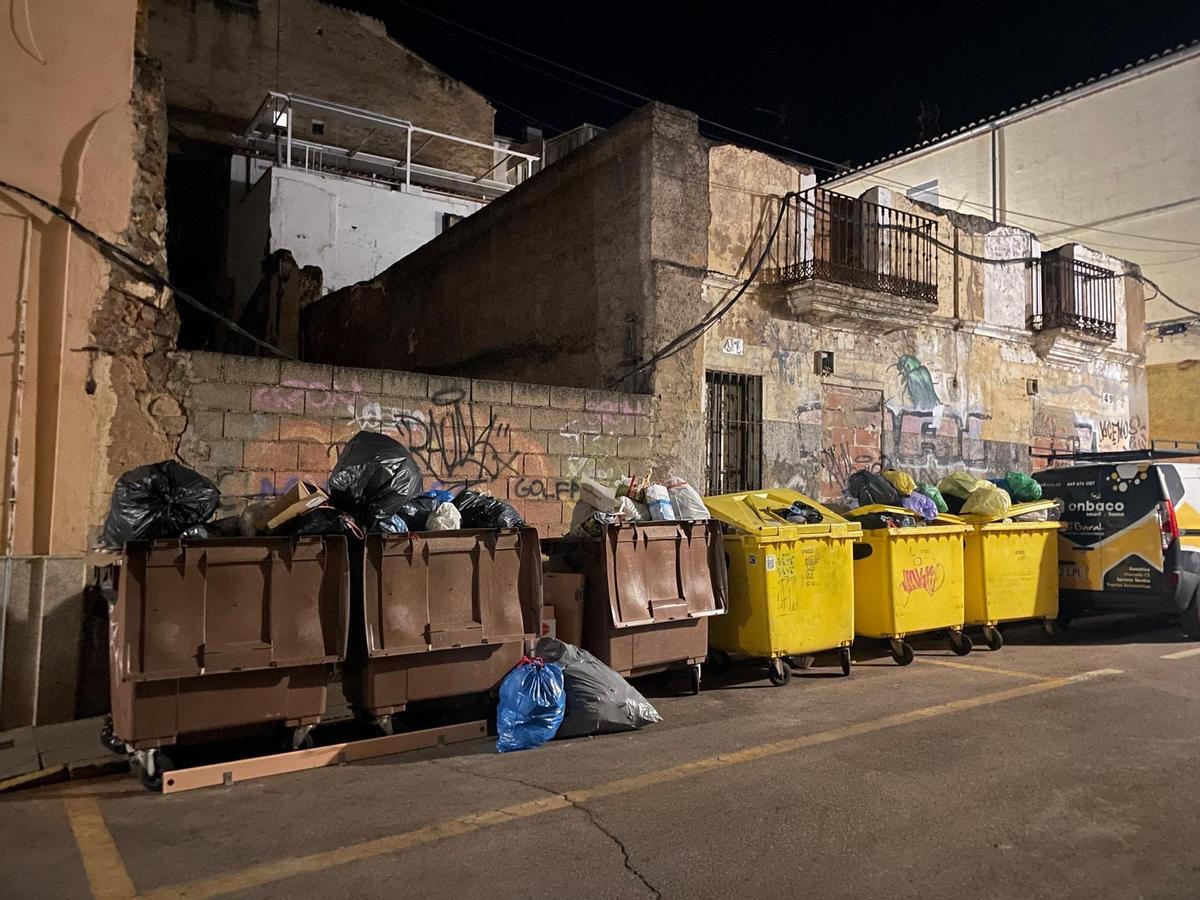 Bolsas de basura encima de las tapas de los contenedores y por fuera de ellos.