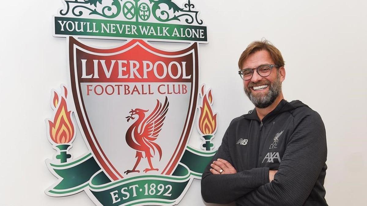 Jürgen Klopp posa junto al escudo del Liverpool en las dependencias de la ciudad deportiva de Melwood.
