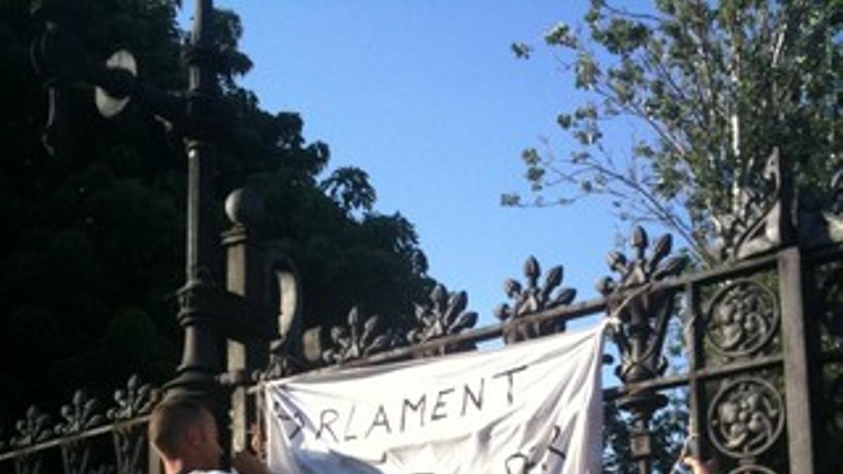 Indigados cuelgan una pancarta en la puerta de la Ciutadella: &quot;Cerrado por revolución&quot;.