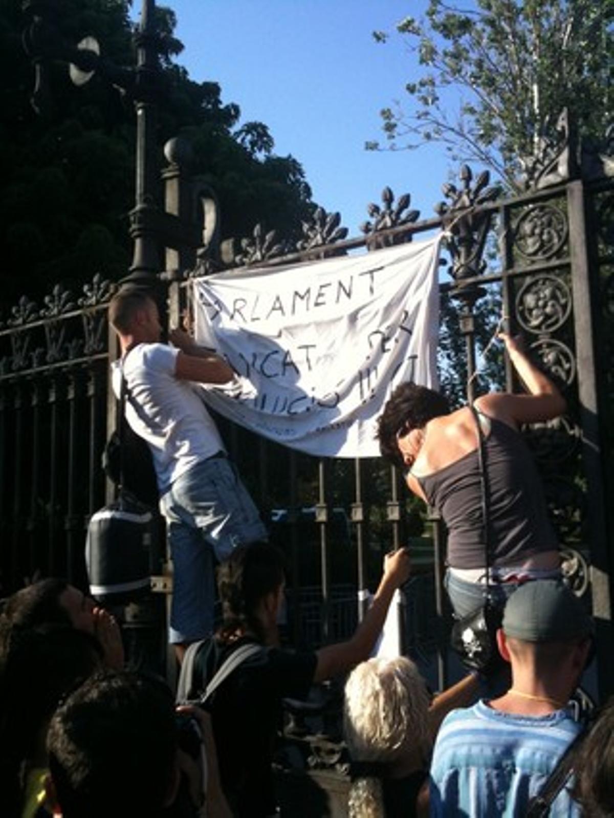 Indignats pengen una pancarta a la porta de la Ciutadella: Tancat per revolució.