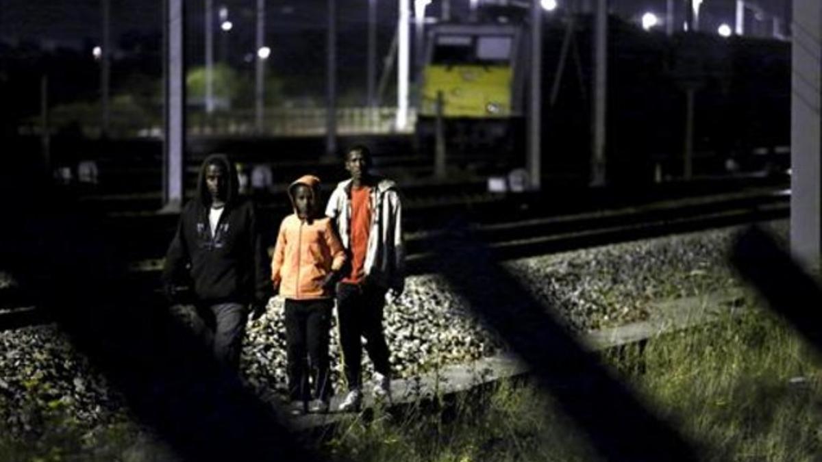 Tres inmigrantes se encaminan por las vías del tren con la intención de acceder al Eurotúnel, cerca de Calais.